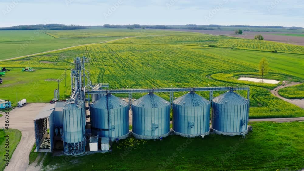 Aerial view over agro silos granary elevator on agro-processing manufacturing plant for processing drying cleaning and storage of agricultural products. Farm building and grain storage bins Aerial view over agro silos granary elevator on agro-processing manufacturing plant for processing drying cleaning and storage of agricultural products. Farm building and grain storage bins