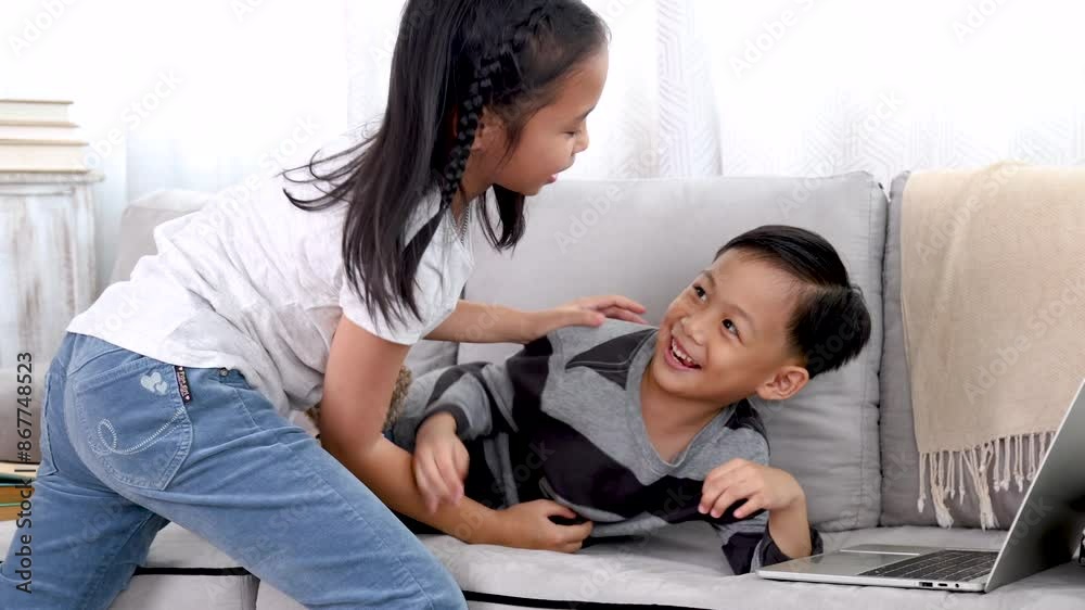 Asian sibling brother and sister share a laugh on a cozy sofa, happy children laugh bonding love relationship at home playtime, family lifestyle, enjoy carefree weekend, health care for kids concept Asian sibling brother and sister share a laugh on a cozy sofa, happy children laugh bonding love relationship at home playtime, family lifestyle, enjoy carefree weekend, health care for kids concept