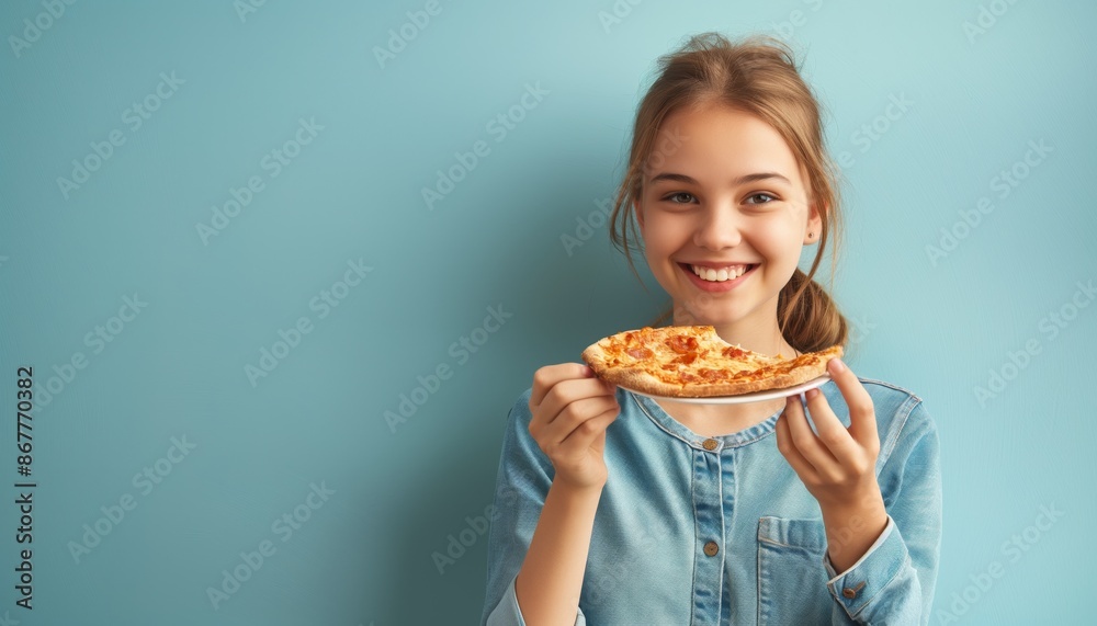 A young girl with a bright smile holds a delicious slice of pizza in one hand, exuding joy and excitement, while standing against a vibrant blue background. A young girl with a bright smile holds a delicious slice of pizza in one hand, exuding joy and excitement, while standing against a vibrant blue background.