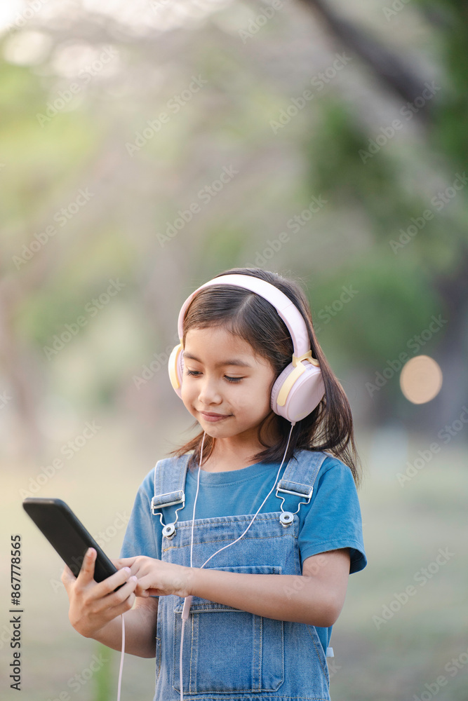 Little girl using smartphone and headphones in nature and having fun. Little girl using smartphone and headphones in nature and having fun.