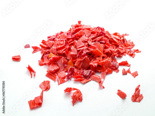 Photos shredded red plastic waste ready for recycling, isolated on white background
