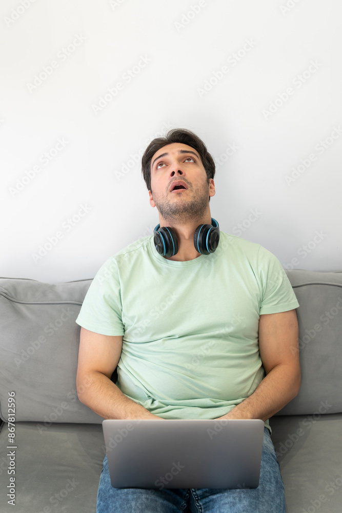 Upset and tired student sitting on the couch and studying online at home. Distance learning concept	