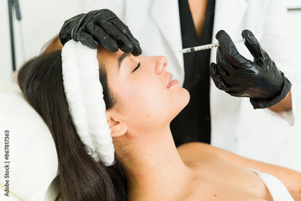 Naklejka premium Skilled doctor in a clinic setting provides a botulinum toxin treatment to enhance the beauty of a young female patient
