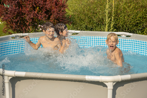 A boy with wet hair is enthusiastically swimming in a pool, giving a thumbs-up gesture. Another child can be seen in the background. The scene captures the joy of swimming on a sunny day.