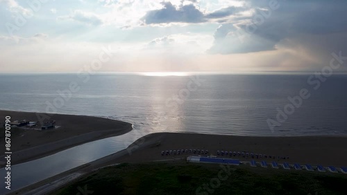 Beautiful flight in summer over the beach in Katwijk aan Zee. People are resting near the sea. Houses for tourists. Beach umbrellas, rides, people swimming in the sea. Beach in Netherland. North Sea. photo