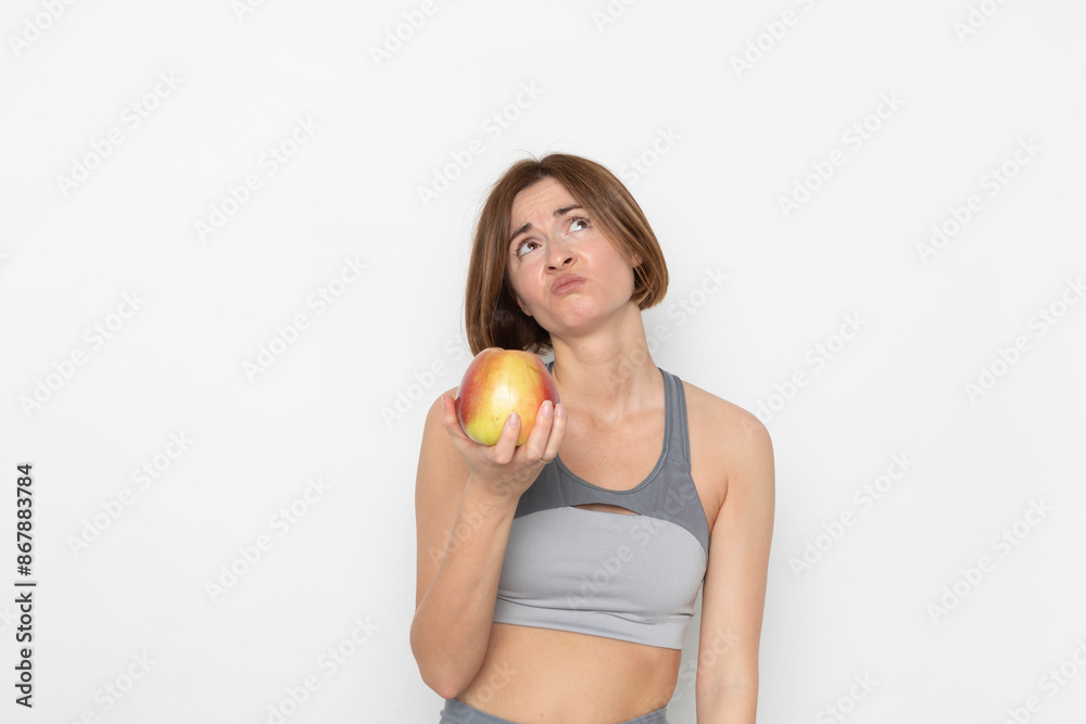 Close up portrait of pretty woman in sportswear holding apple isolated on white background. Healthy lifestyle concept Close up portrait of pretty woman in sportswear holding apple isolated on white background. Healthy lifestyle concept