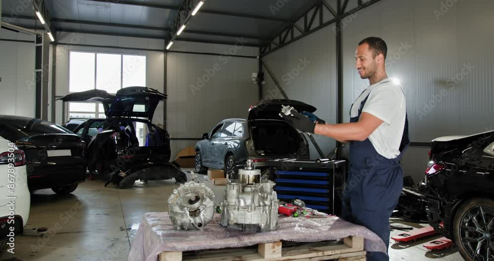 Auto Mechanic Repairing Electric Car Engine in Workshop. Auto mechanic working in a modern workshop, examining an electric car engine. Various vehicles in different stages of repair around him. Auto Mechanic Repairing Electric Car Engine in Workshop. Auto mechanic working in a modern workshop, examining an electric car engine. Various vehicles in different stages of repair around him.