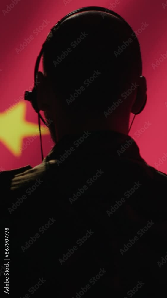 Vertical video Military dispatcher working for Chinese Communist Party providing informations for troops using headset. Radio communications operator isolated over China flag background coordinating Vertical video Military dispatcher working for Chinese Communist Party providing informations for troops using headset. Radio communications operator isolated over China flag background coordinating