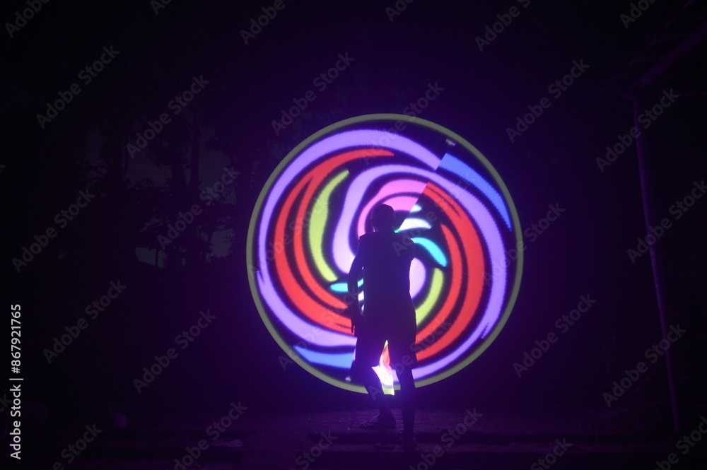 One person standing alone against a Colourful circle light painting as the backdrop One person standing alone against a Colourful circle light painting as the backdrop