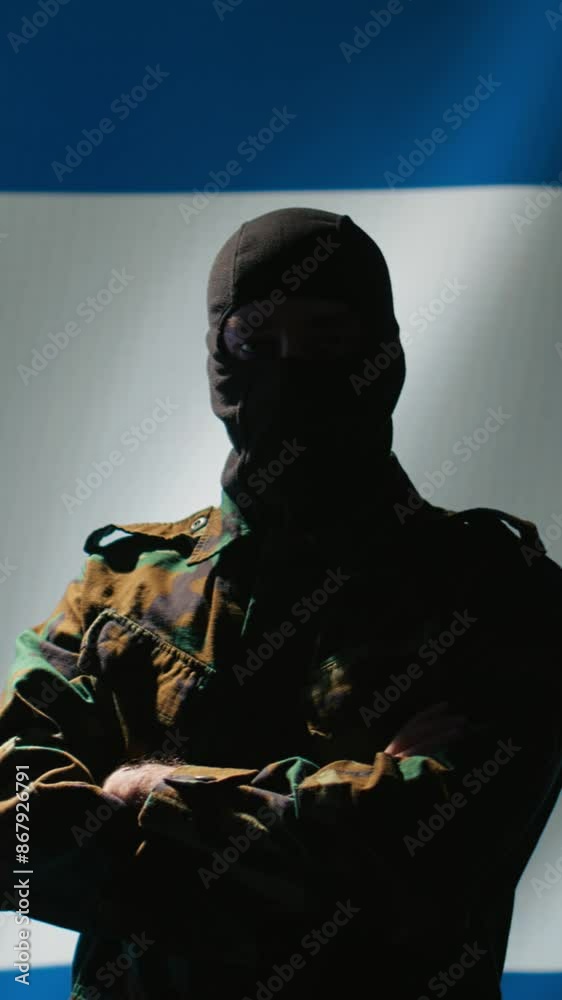 Vertical video Mossad operator wearing mask to remain anonymous standing proud in front of Israel flag, feeling pride in serving country. Israeli secret agent in command room crossing arms, camera B Vertical video Mossad operator wearing mask to remain anonymous standing proud in front of Israel flag, feeling pride in serving country. Israeli secret agent in command room crossing arms, camera B