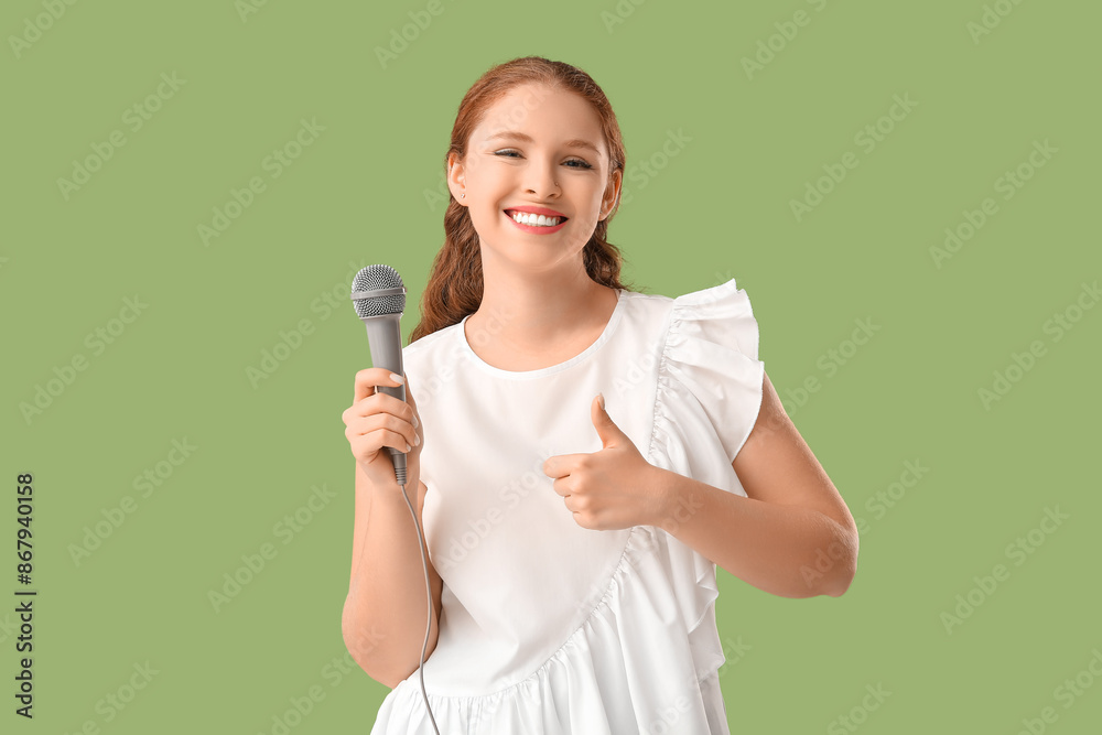 Beautiful young woman with microphone showing thumb-up gesture on green background Beautiful young woman with microphone showing thumb-up gesture on green background