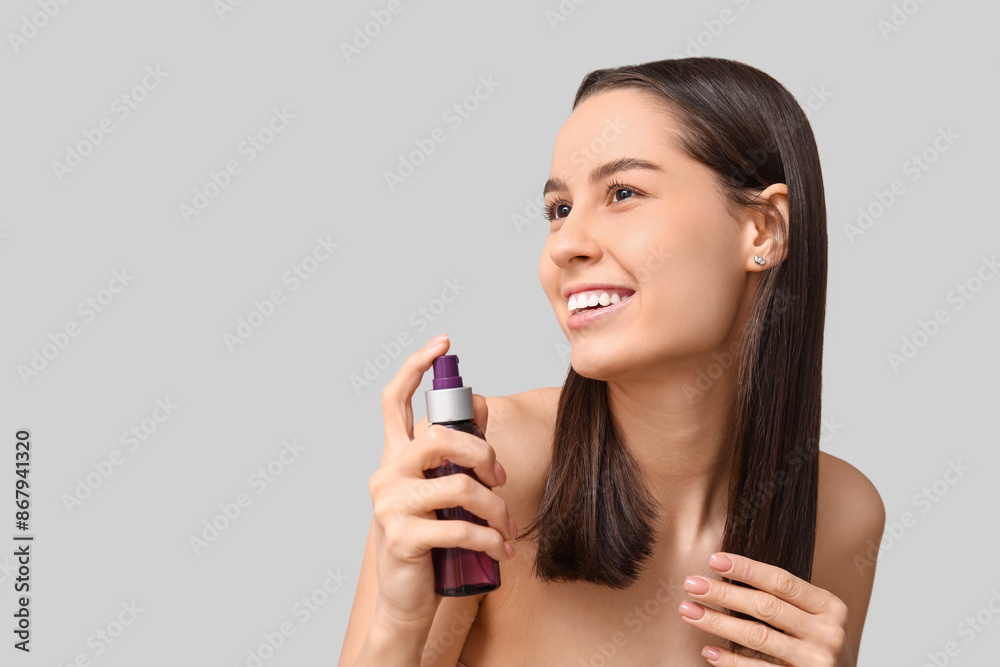 Young woman with cosmetics for hair treatment on grey background Young woman with cosmetics for hair treatment on grey background