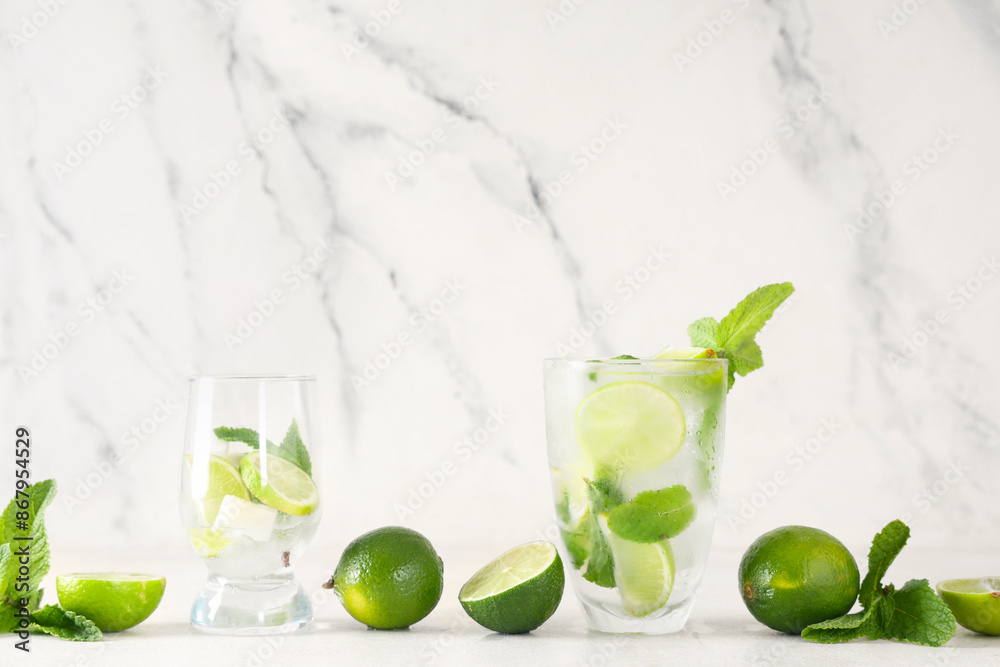 Fototapeta premium Glasses of fresh Mojito cocktail with limes and mint on white background