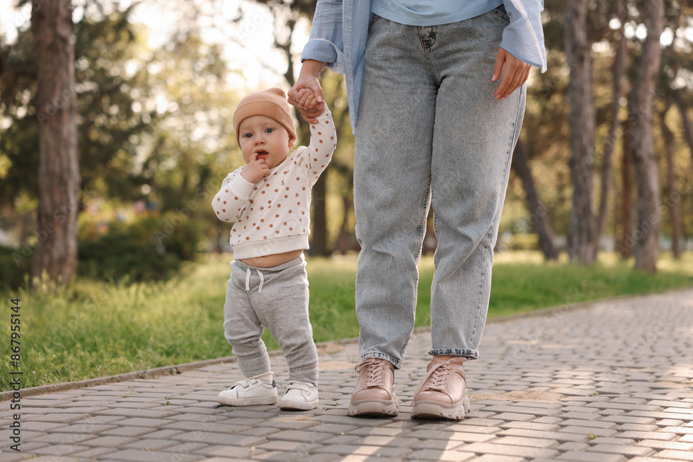 Obraz premium Mother supporting her baby while he learning to walk outdoors, closeup