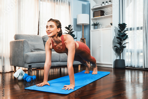 Athletic and sporty woman doing pushup on fitness mat during home body workout exercise session for fit physique and healthy sport lifestyle at home. Gaiety home exercise workout training.