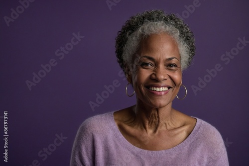 African American female person with smile on face next to empty space on dark purple background. Beautiful mature woman. Place for advertising text.