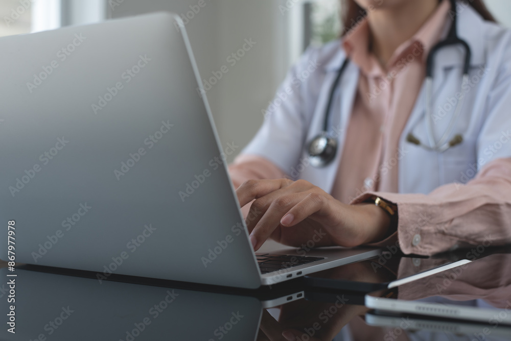 Female doctor working on laptop computer at doctor's office. writing prescripstion, recording patient's information, healthcare and medicine concept Female doctor working on laptop computer at doctor's office. writing prescripstion, recording patient's information, healthcare and medicine concept