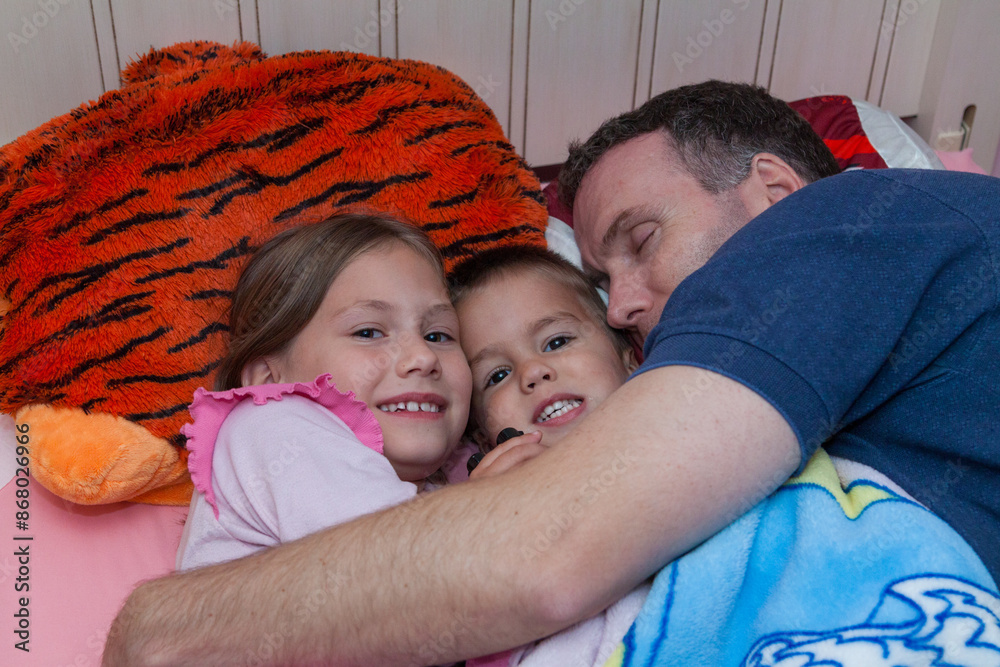 father snuggling with daughter and toddler son father snuggling with daughter and toddler son