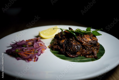 Traditional South Indian Kerala Style beef roast on banana leaf on a white serving plate in the restaurant