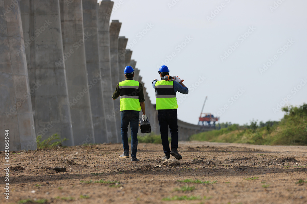 Obraz premium Pile construction: A civil engineer and technician are conducting a survey with a camera along the old railway for the construction of new electric train piles