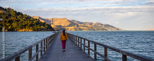 long hair girl enjoys a walk on governors bay jetty at sunset; new zealand south island, canterbury region, little bay between lyttelton and banks peninsula