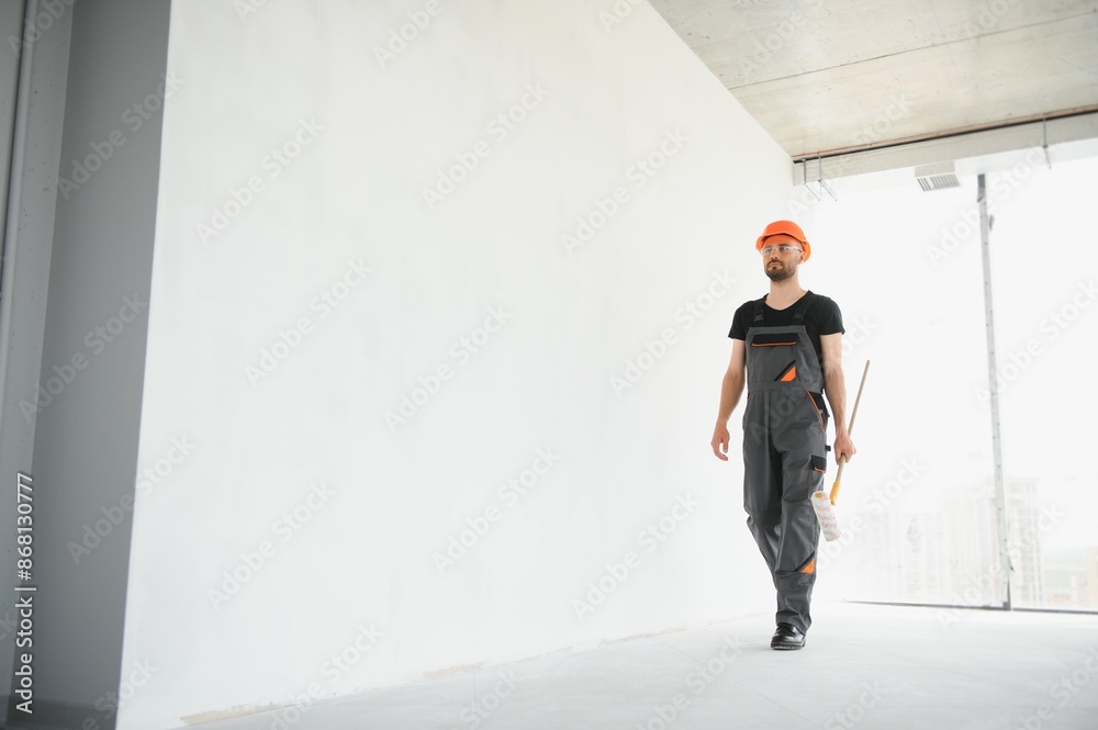 Portrait of man holding paint roller while painting white wall and making renovation Portrait of man holding paint roller while painting white wall and making renovation