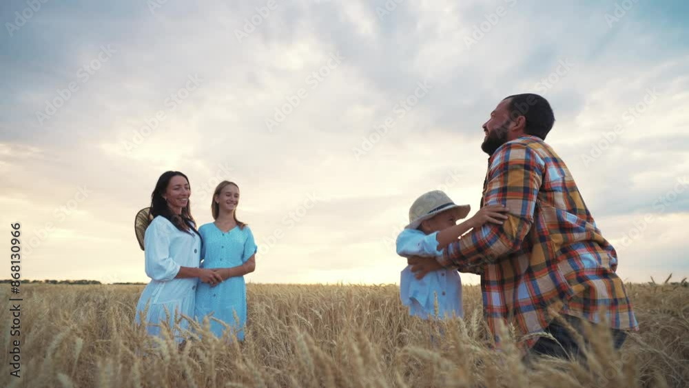 Happy family dad, mom, son and daughter walk on wheat field at sunset in summer. Father throws son in air, plays with him, mother and teen girl smiling. Relaxed people having good weekend together. Happy family dad, mom, son and daughter walk on wheat field at sunset in summer. Father throws son in air, plays with him, mother and teen girl smiling. Relaxed people having good weekend together.