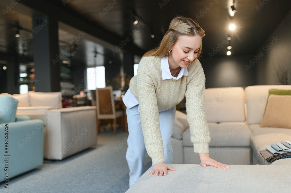 Happy young woman chooses sofa for home in furniture store Happy young woman chooses sofa for home in furniture store