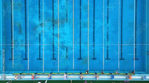 The start of a swimming competition in an outdoor pool: swimmers are diving into the water and beginning to swim