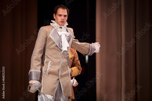 A guy in an eighteenth century costume plays on stage