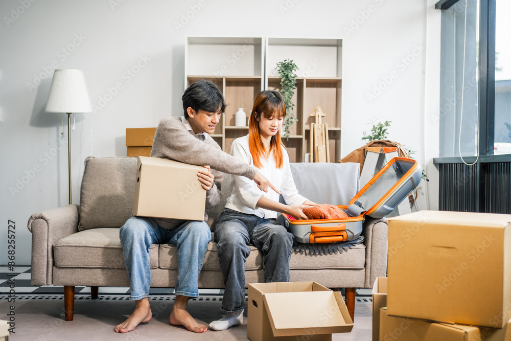 A young couple sits on the sofa, happily packing their belongings into boxes for a move to a new home. They share smiles and excitement, ready for a new chapter together. A young couple sits on the sofa, happily packing their belongings into boxes for a move to a new home. They share smiles and excitement, ready for a new chapter together.