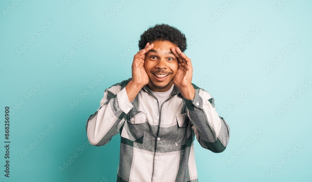 Stunned young man smiling at camera in blue studio Stunned young man smiling at camera in blue studio