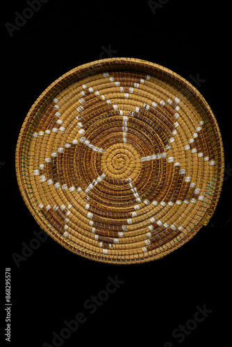 Traditional South African woven basket with geometric paterns on a black background.