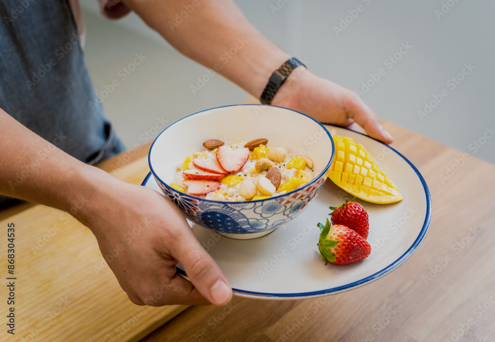 Chef at the kitchen preparing bowl of oats with strawberries and mango Chef at the kitchen preparing bowl of oats with strawberries and mango