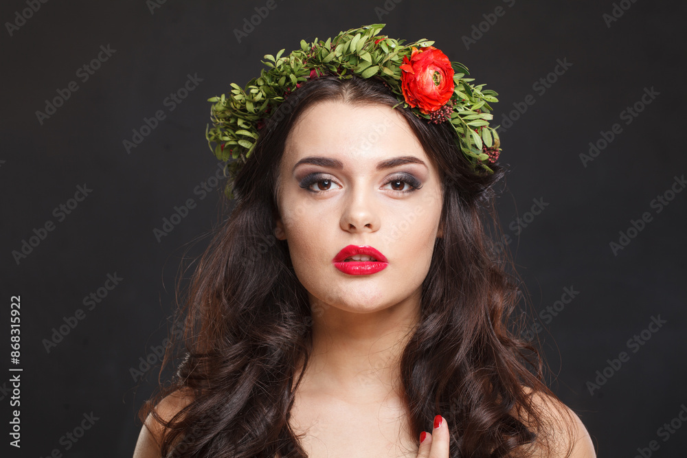 Naklejka premium Glorious young woman with floral head wreath looking at camera while standing against black background