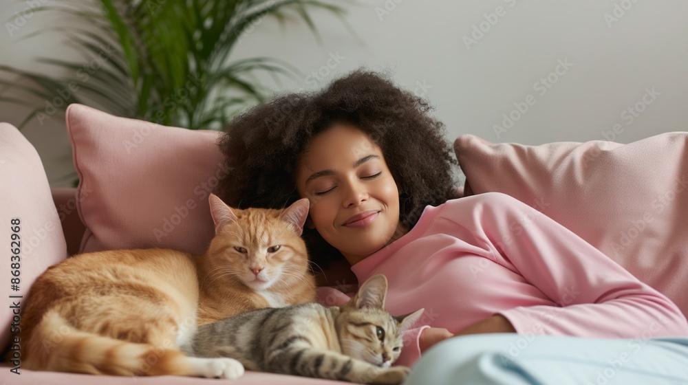 A woman is sleeping on a couch with two cats on her lap. The cats are orange and black A woman is sleeping on a couch with two cats on her lap. The cats are orange and black
