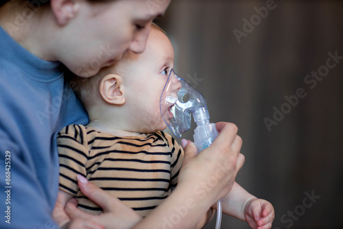 Woman with infant son makes inhalations using a nebulizer at home