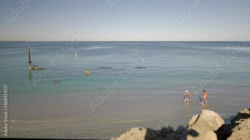 Coastal view overlooking submerged wreck off the Omeo with snorkelers exploring, walkers and swimmers relaxing beneath sunny clear sky offshore Perth Western Australia