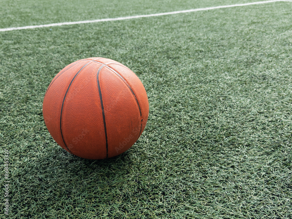 Orange basket ball lying on green playground. Orange basket ball lying on green playground.