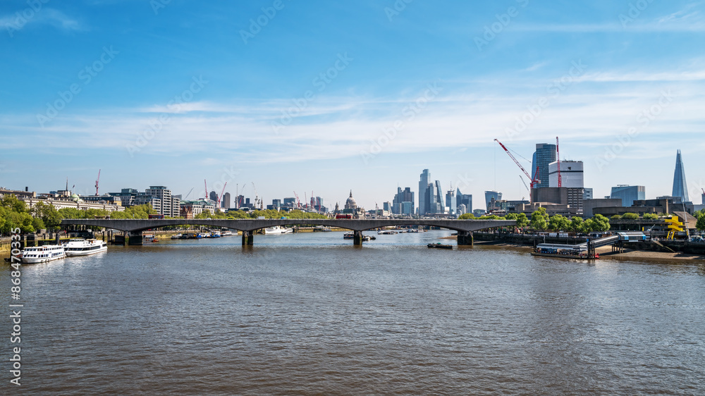 Obraz premium Looking along the river Thames to Waterloo Bridge, with St Pauls Cathedral and the City of London beyond. Panoramic view in summer.