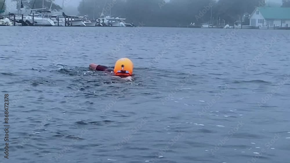 Close up of a women swimming in a canal wearing on orange safety flotation buoy. Close up of a women swimming in a canal wearing on orange safety flotation buoy.
