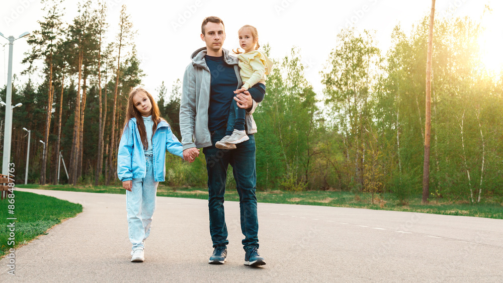 Father walking with his little daughters in park Father walking with his little daughters in park
