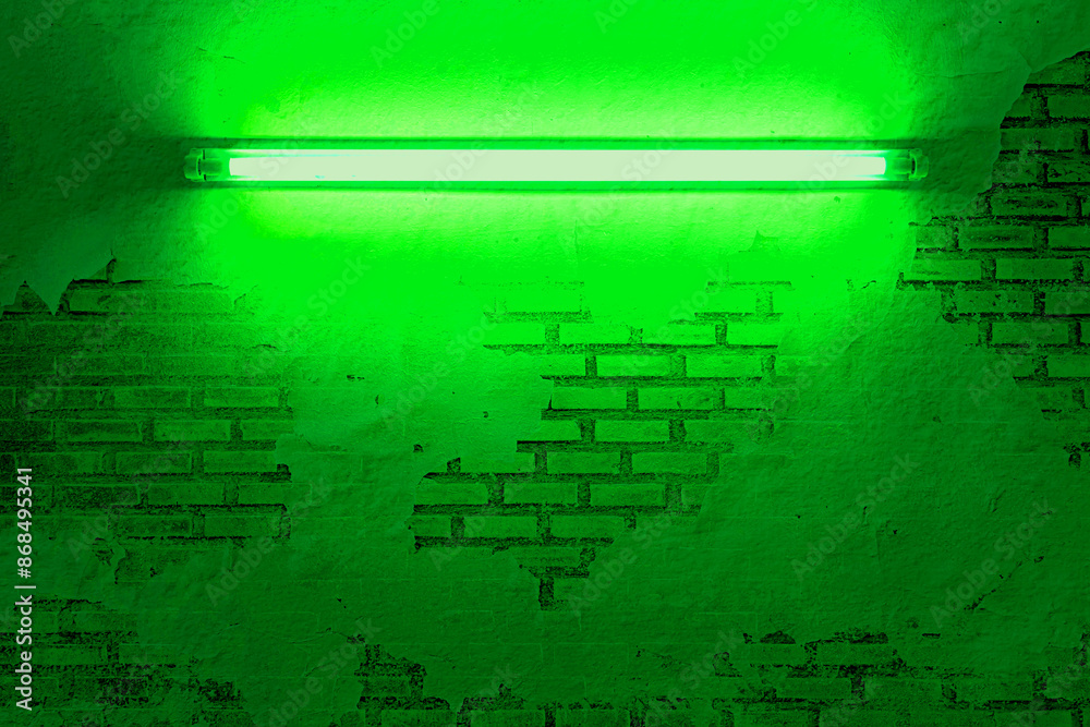 Fototapeta premium green neon light bulb on brick wall. Background texture of empty old brick wall with glowing green neon lamps. 
