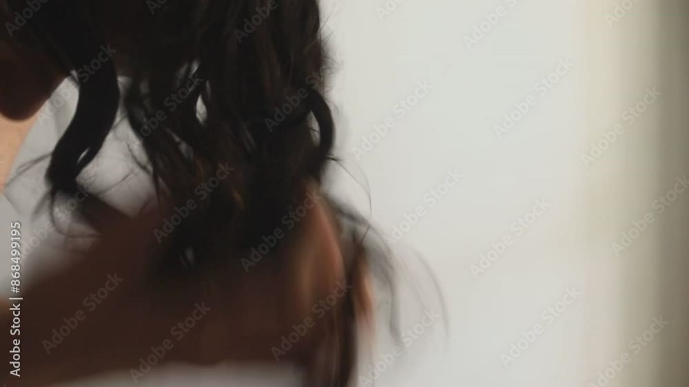 Woman applies a balm or condition styling to wet hair using the praying hands technique