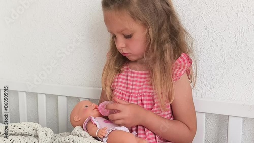 little girl hold doll and play mother daughter game, light tones room on background, role-playing