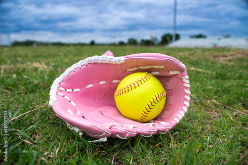 Green softball in pink softball glove on field