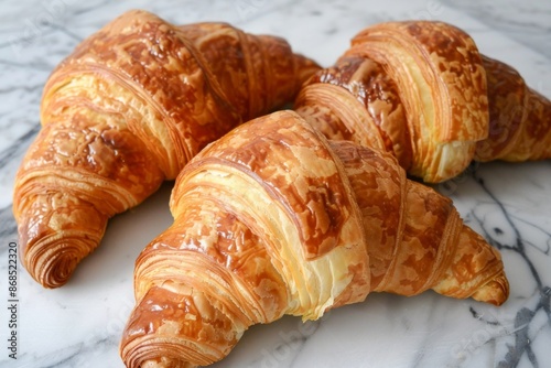 Three Golden Brown Croissants on a Marble Surface
