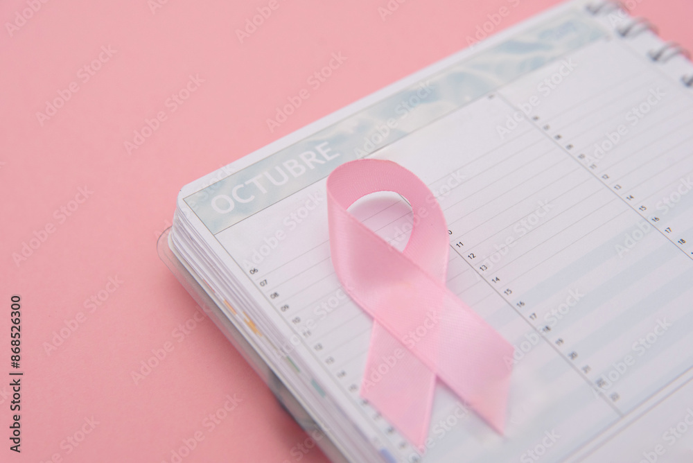 pink ribbon symbol of breast cancer awareness on calendar isolated on pastel pink background with copy space pink ribbon symbol of breast cancer awareness on calendar isolated on pastel pink background with copy space