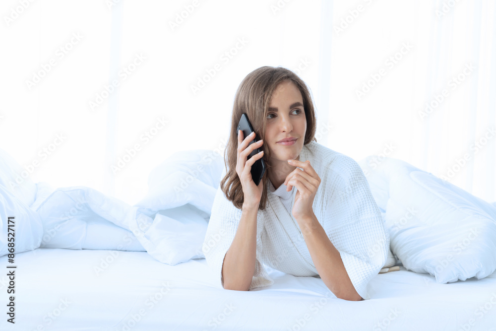 woman using Smartphone on bed to check Social media and morning news while wake up woman using Smartphone on bed to check Social media and morning news while wake up