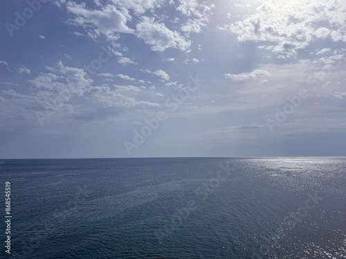 Photography Ocean blue water with sun glare and sky clouds